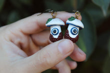 Load image into Gallery viewer, Two White and Blue Mushroom Earrings with Evil Eye, Leaves, and Textured Dirt.
