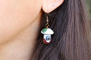 Model wearing White and Blue Mushroom Earrings with Evil Eye, Leaves, and Textured Dirt.